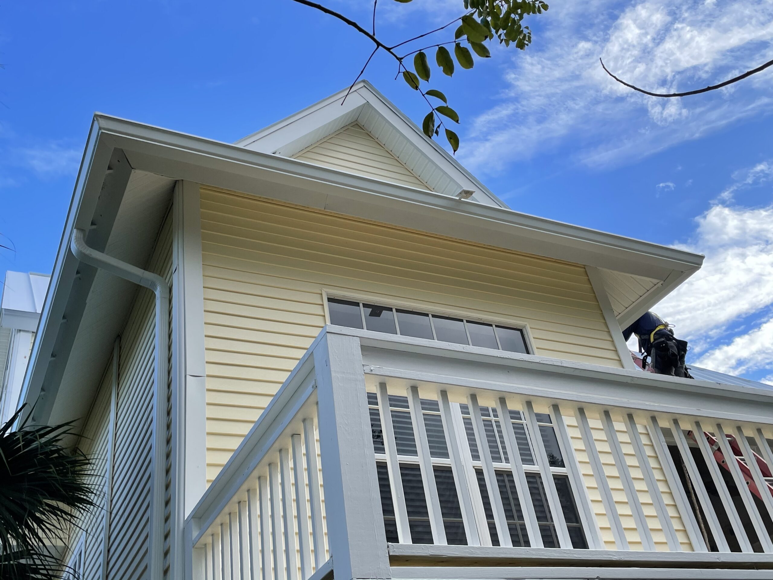 img-seemless-gutters-yellow-house-man-on-roof